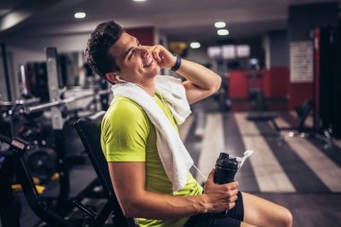 Yakışıklı sporcu dinleniyor, egzersiz yaptıktan sonra içme suyu molası veriyor.