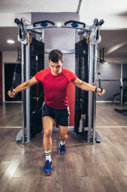 Spor salonunda egzersiz yapan yakışıklı bir genç.