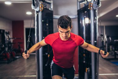 Spor salonunda egzersiz yapan yakışıklı bir genç.