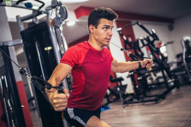 Spor salonunda egzersiz yapan yakışıklı bir genç.