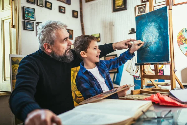 Father and son working and painting together in art studio