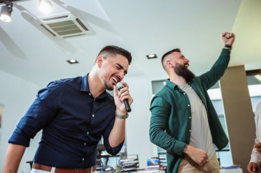 Modern ofiste karaoke yapan bir grup profesyonel insan.