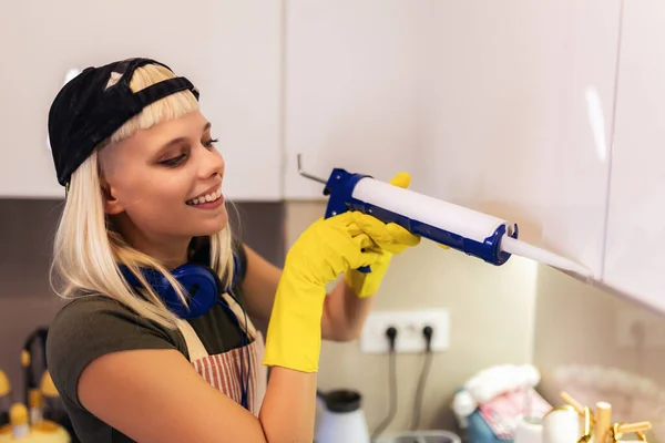 Woman working with silicone glue. Caulking the kitchen