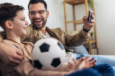 Baba ve oğul patlamış mısır yerken futbol maçı izliyorlar..