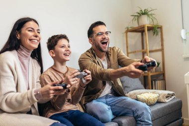 Anne, baba ve oğul video oyunu oynuyor ve birlikte vakit geçiriyorlar..