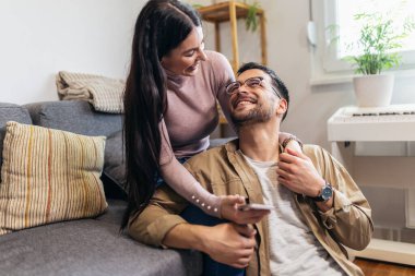 Mutlu genç çift kanepede dinleniyor ve sarılıyorlar.