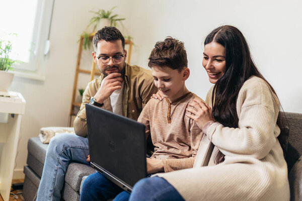 Mother, father and son playing video games together and spending time together.