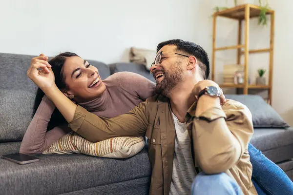 Happy young couple relax on sofa at home hugging