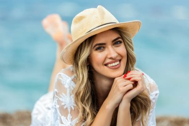 Güzel genç bir kadın kumsalda uzanıyor, güzel günün tadını çıkarıyor..