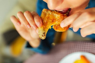 Tavuk bacağı yiyen bir kadının yakın çekimi.