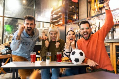 Heyecanlı futbol taraftarları barda futbol maçı izlerken kutlama yapıyorlar..