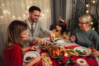 Mutlu çok nesilli aile evde birlikte yemek yiyor. Evde Noel yemeğinde aile.