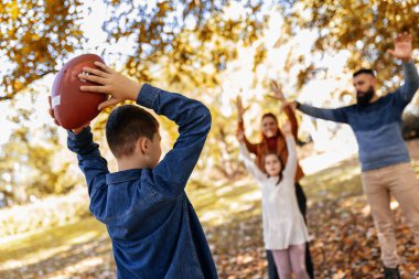 Aile parkta Amerikan futbolu oynuyor. Aile ve çocuklar, doğa konsepti..