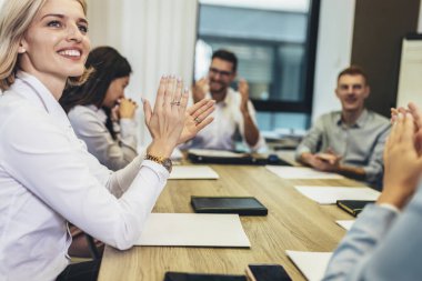 Office colleagues having discussion during meeting in conference room. Group of men and women sitting in conference room and smiling.