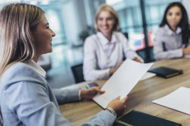 Office colleagues having discussion during meeting in conference room. Group of men and women sitting in conference room and smiling.