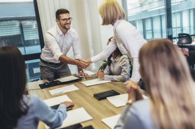Office colleagues having discussion during meeting in conference room. Group of men and women sitting in conference room and smiling.