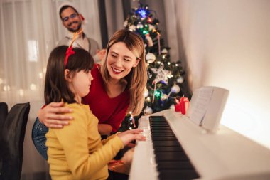 Aile, kızlarının Noel zamanı piyano çalarken dinlediği müzikle eğleniyor.