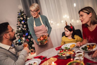Mutlu çok nesilli aile evde birlikte yemek yiyor. Evde Noel yemeğinde aile.