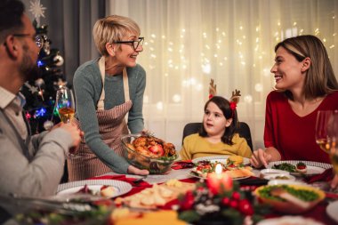 Mutlu çok nesilli aile evde birlikte yemek yiyor. Evde Noel yemeğinde aile.
