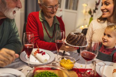 Mutlu bir aile Noel 'de büyükannesi ve büyükbabasıyla yemek yiyor. Ev yapımı yemekler yemek, içecekler içmek. Ev yeni yıl arifesi ve Noel için dekore edilmiştir.