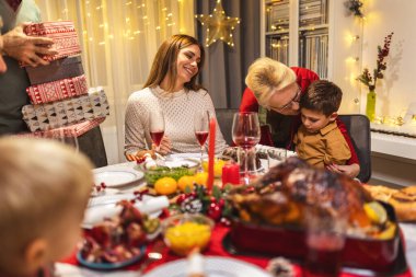 Büyükbabalar torunlarına Noel arifesinde hediye veriyorlar. Aile yemek yiyor..