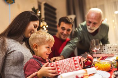 Büyükbabalar torunlarına Noel arifesinde hediye veriyorlar. Aile yemek yiyor..