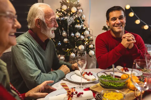 Mutlu bir aile Noel 'de büyükannesi ve büyükbabasıyla yemek yiyor. Ev yapımı yemekler yemek, içecekler içmek. Ev yeni yıl arifesi ve Noel için dekore edilmiştir.