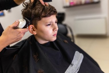 Cute young boy getting a haircut by hairdresser