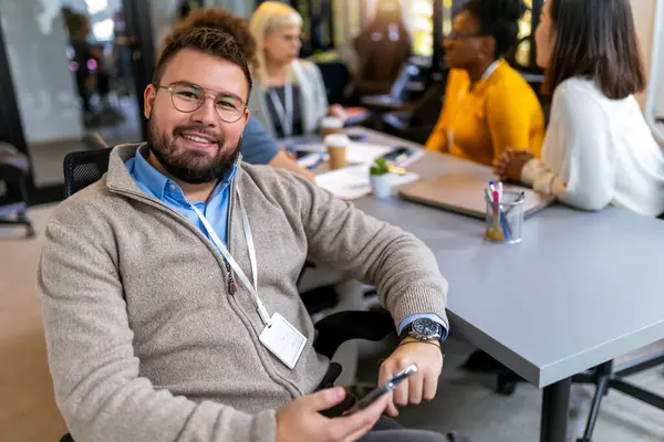 Man Employee Smiling in the Office, With his Colleagues in Background.