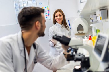 Doktor, laboratuarında araştırma yaparken mikroskoba bakıyor.