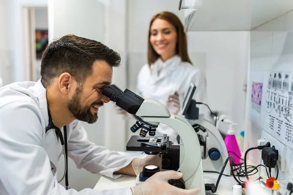 Doctor looking thru microscope while doing research in his lab