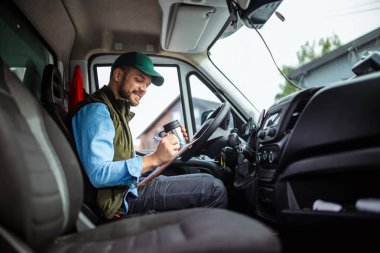 Çekici servisinde çalışan yakışıklı genç adam biraz enerji toplayabilmek için kahve içiyor.