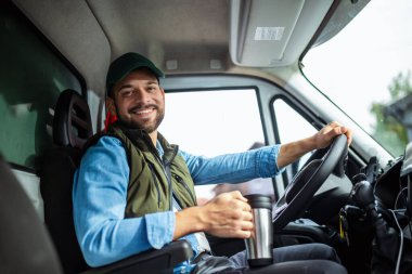 Çekici servisinde çalışan yakışıklı genç adam biraz enerji toplayabilmek için kahve içiyor.