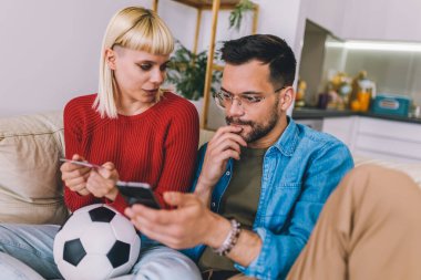 Genç çift dijital tabletten futbol maçı izliyor ve online bahis için kredi kartı kullanıyorlar..