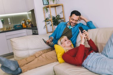 Kanepede sarılan, dijital tablet ve telefon kullanan güzel bir çift..