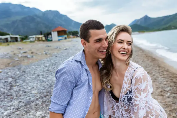 Happy young couple laughing and holding hands on the beach
