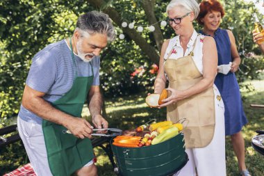 Yaşlı insanlar barbekü yapıyor, içki içiyor, hatıralar yaratıyor ve gülüyorlar..