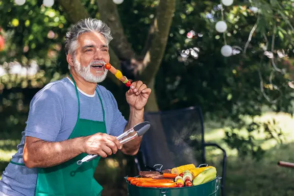 Happy man preparing food on barbecue.