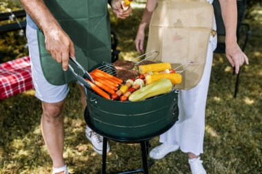 Yaşlı insanlar barbekü yapıyor, içki içiyor, hatıralar yaratıyor ve gülüyorlar..