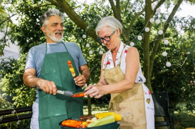 Yaşlı insanlar barbekü yapıyor, içki içiyor, hatıralar yaratıyor ve gülüyorlar..
