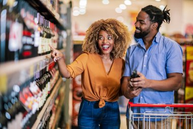 Alışveriş merkezinde market alışverişi yapan Afro-Amerikalı bir çift. Şarap alıyorum..