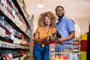 Alışveriş merkezinde market alışverişi yapan Afro-Amerikalı bir çift. Şarap alıyorum..