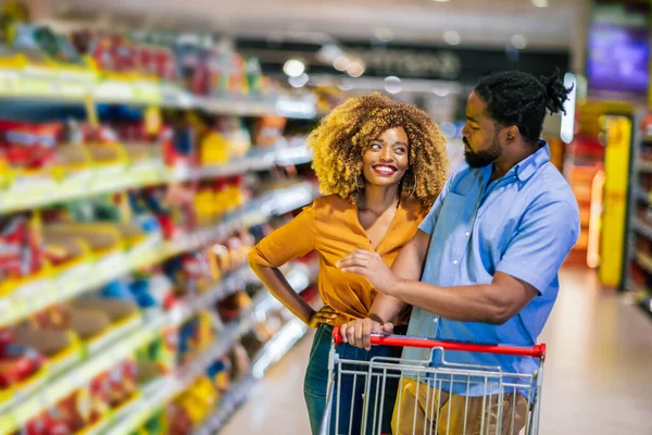 African American couple with trolley purchasing groceries at mall