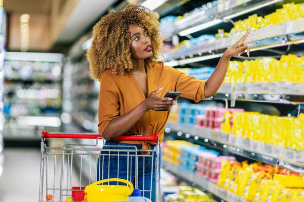 African American Woman Buying Food In Grocery Shop, And Using Phone.