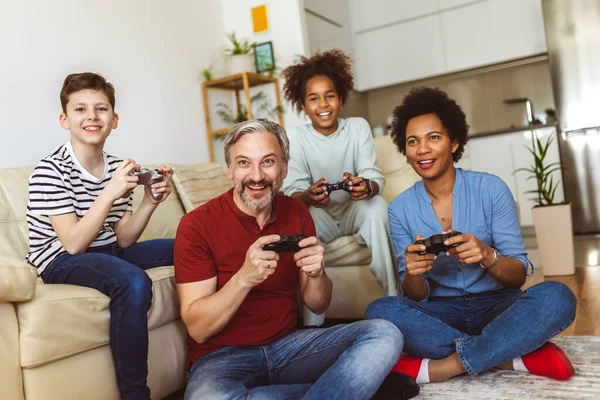 Smiling family enjoying time together at home sitting on sofa in living room and playing video games.