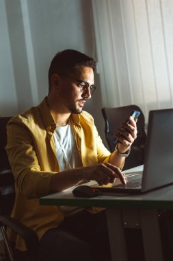 Genç işadamı geç saatlere kadar ofisinde çalışıyor. Telefonuna bakıyorum..