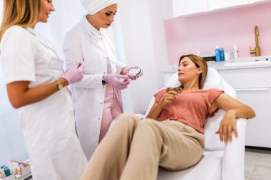 Dermatolog mol veya akne olan bir dermatoscope hastanın inceliyor. Melanom önleme