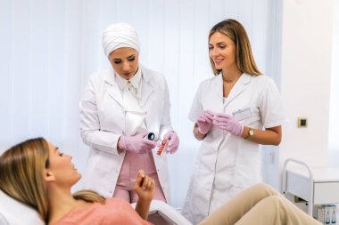 Dermatolog mol veya akne olan bir dermatoscope hastanın inceliyor. Melanom önleme