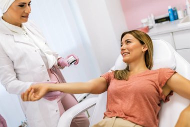 Dermatolog mol veya akne olan bir dermatoscope hastanın inceliyor. Melanom önleme