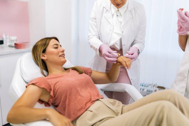 Doktor hastanın ellerine koruyucu krem sürüyor.